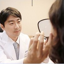 흰 가운 의사가 손거울을 든 환자와 1:1 상담하는 모습