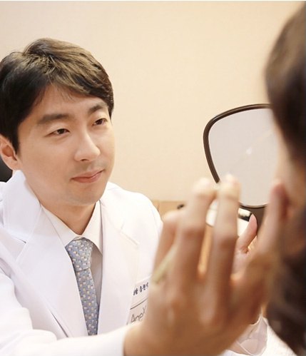 흰 가운을 입은 의료진이 손거울을 든 환자와 마주보며 상담하는 장면