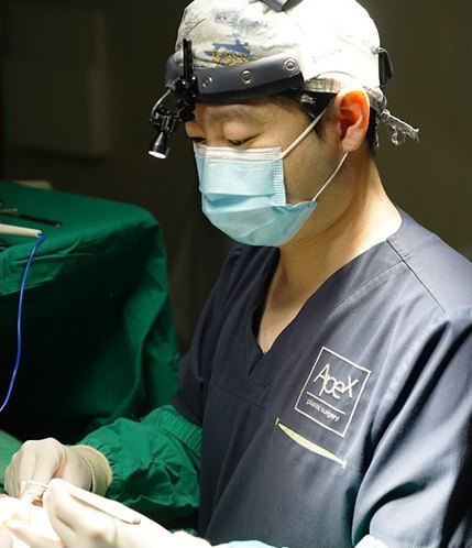 수술모와 확대경 헤드라이트, 마스크를 착용한 의료진이 수술 중인 모습