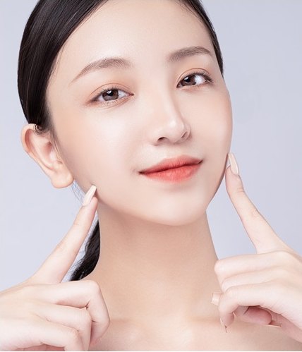 머리를 뒤로 넘긴 여성 모델이 양손 검지로 턱선 양쪽을 가리키는 뷰티 컷
