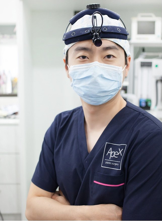 네이비 수술복 차림으로 팔짱을 낀 에이펙스성형외과 의료진